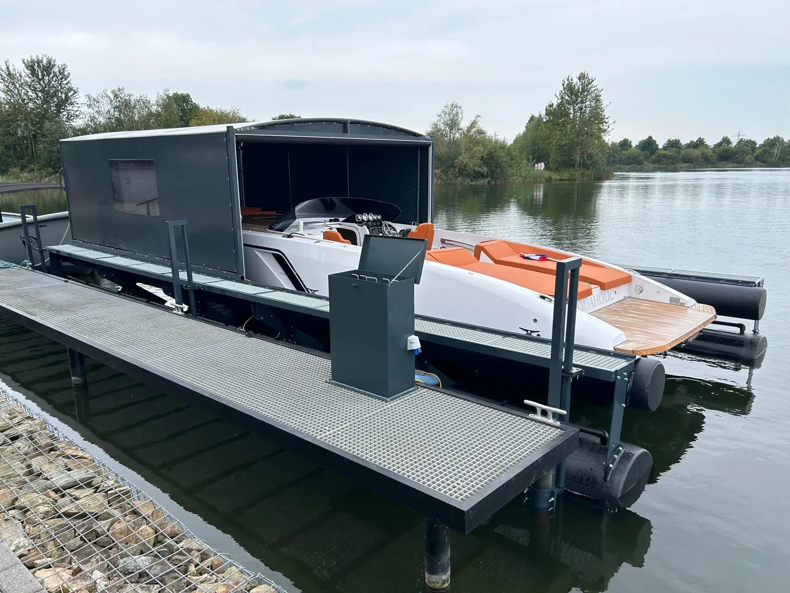Motorboot op een drijvende bootlift onder een geopende grijze bootoverkapping