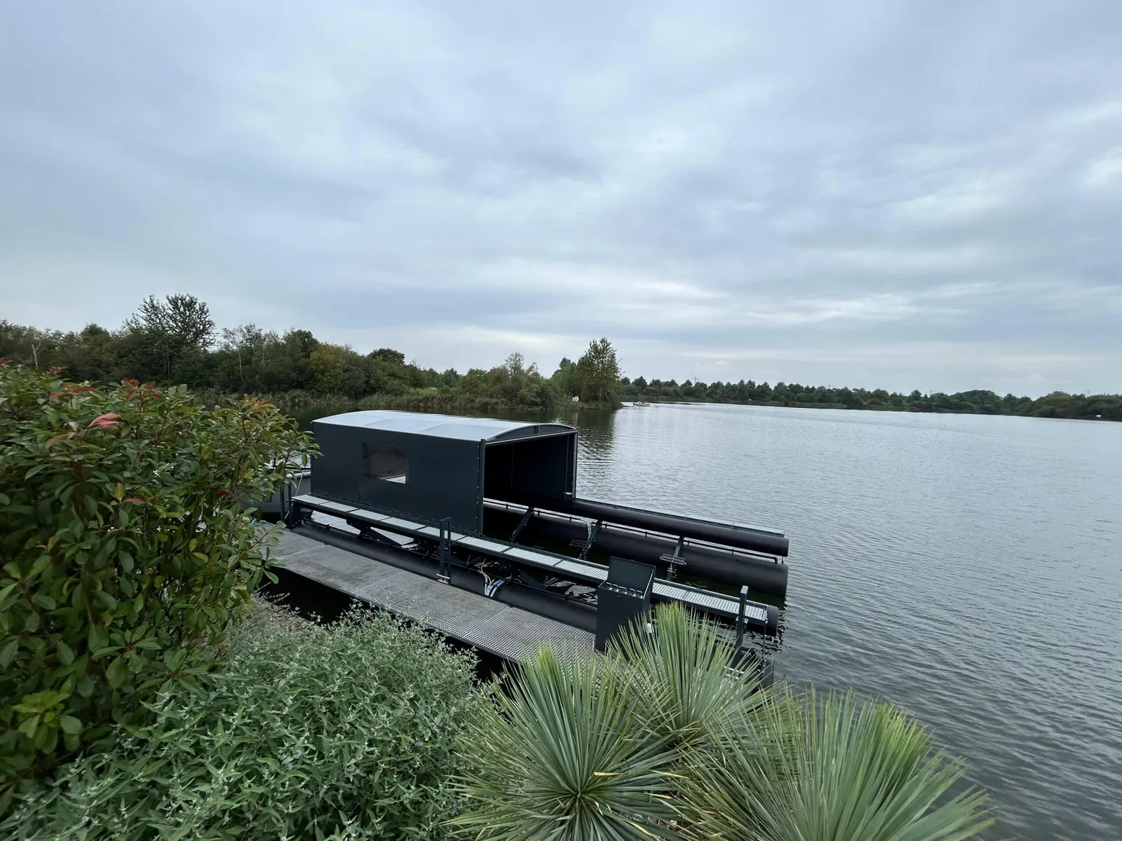 Bootoverkapping met bootlift, gezien vanuit een tuin aan het meer